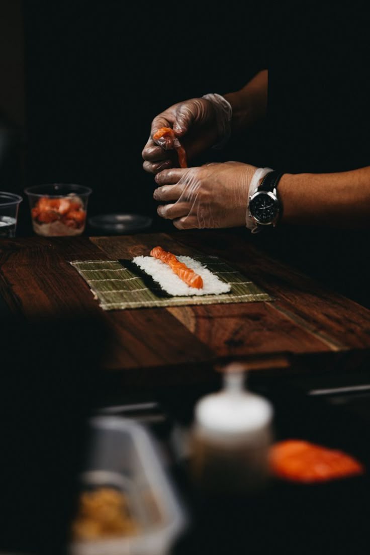 Chef hand-pressing salmon nigiri on a bamboo mat